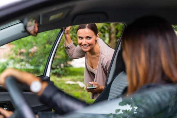 A woman is getting into a car and is looking at the driver